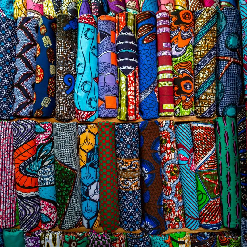 Rows of rolled African wax-print fabrics in bright patterns