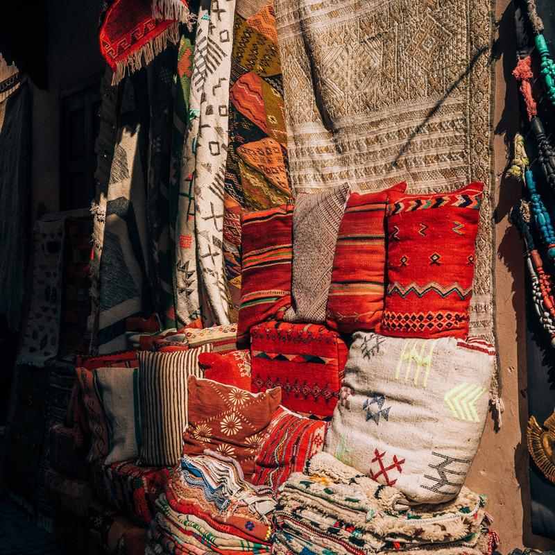 Colourful woven textiles and cushions stacked at a market stall
